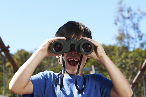 Child using binoculars to look towards the camera.