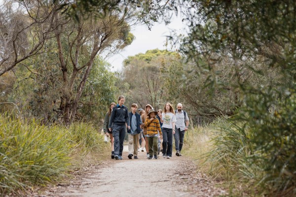 Park ranger leading a multi-age group along a woodland trail.